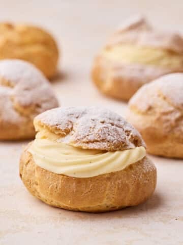 Four choux pastry buns sliced in half and filled with a swirl of creme diplomat.
