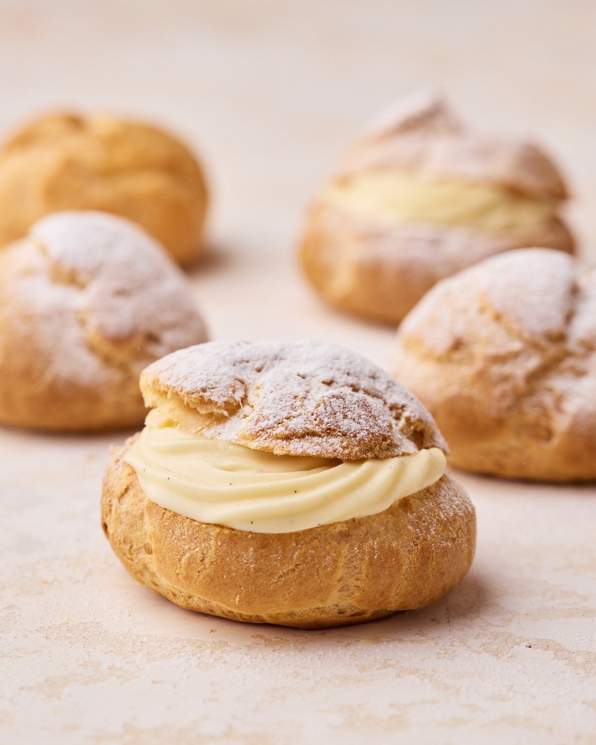 Four choux pastry buns sliced in half and filled with a swirl of creme diplomat. 