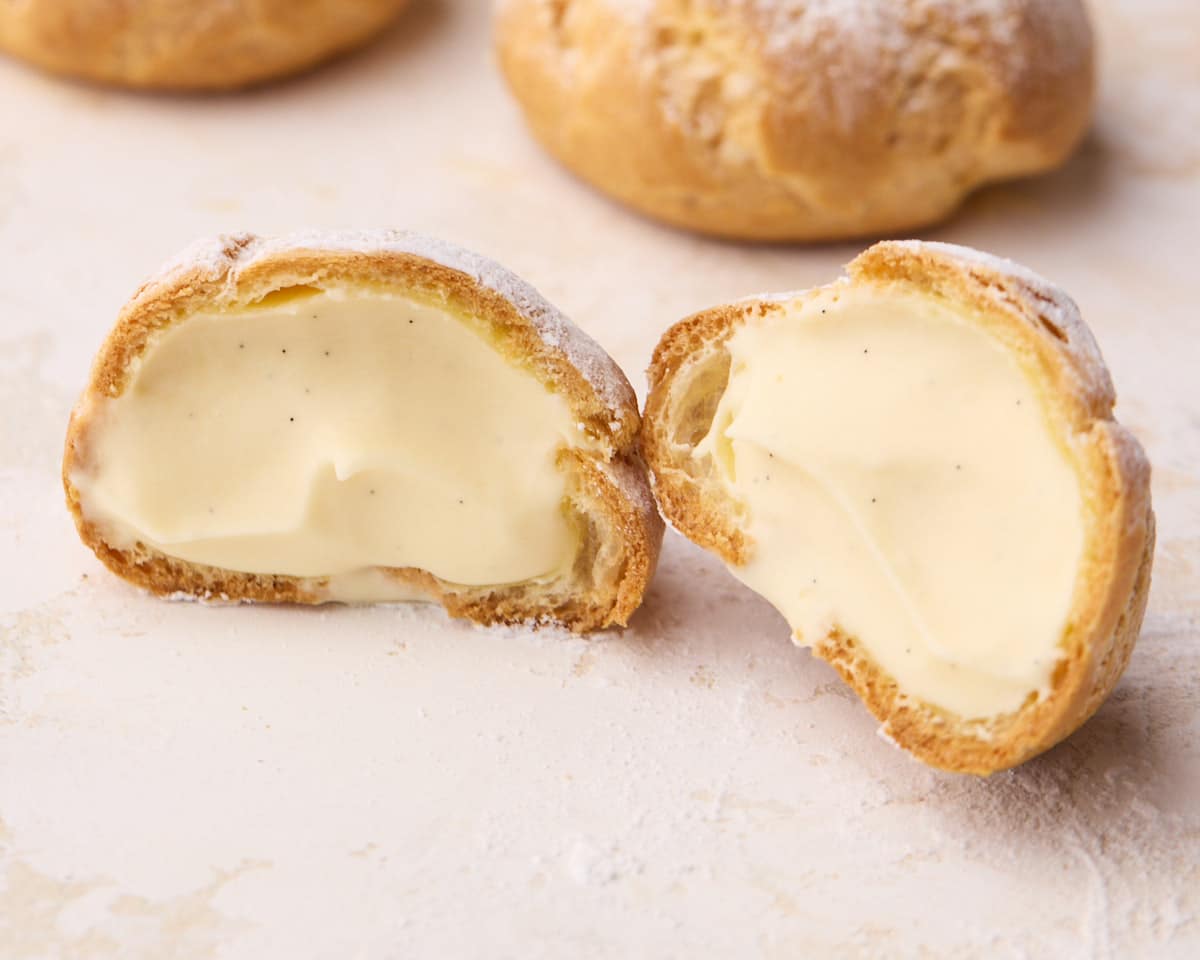 Cream puff sliced in half and opened to show the creamy custard filling on both sides.