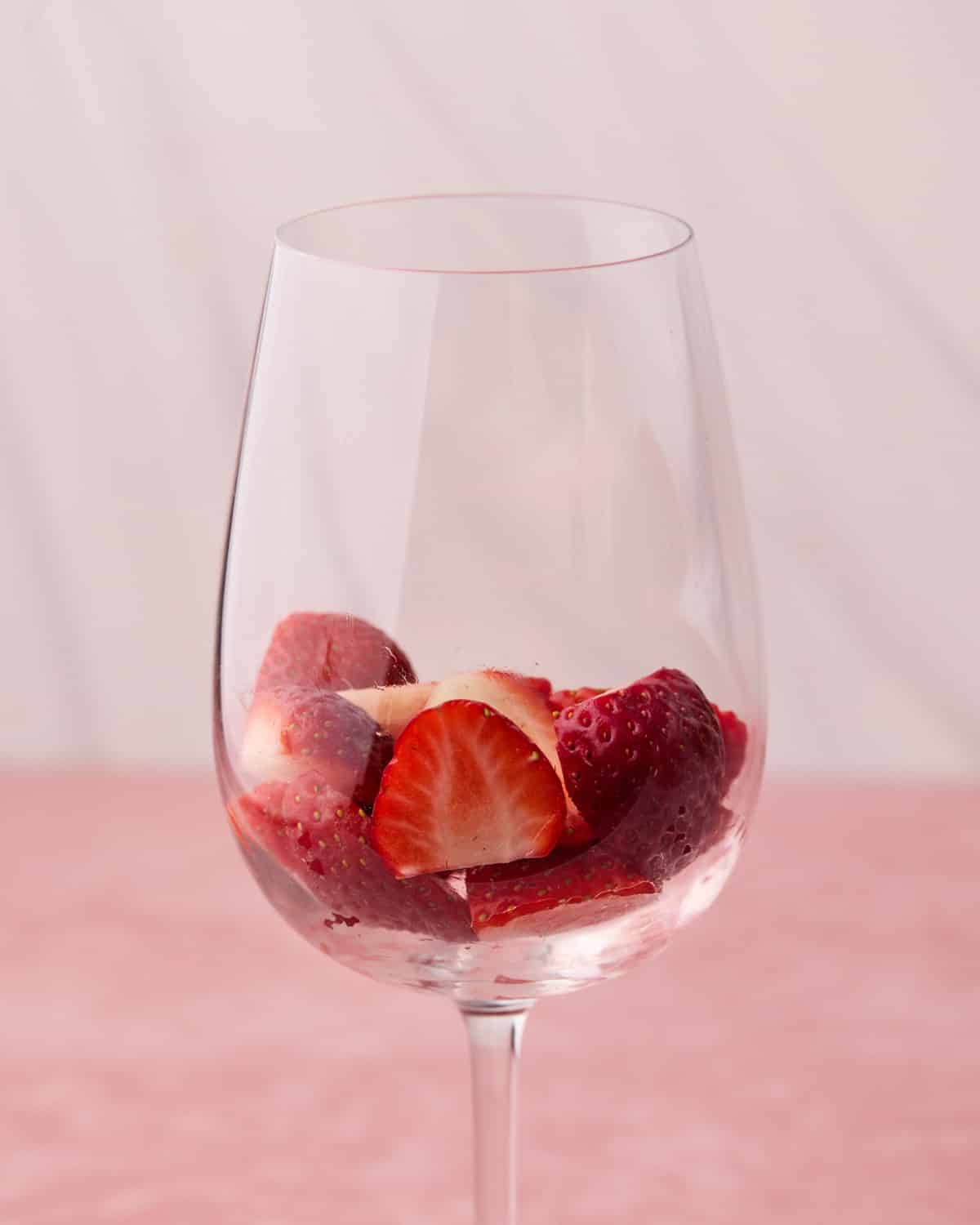Fresh strawberries in a wine glass in the process of building Dubai chocolate strawberry cups.