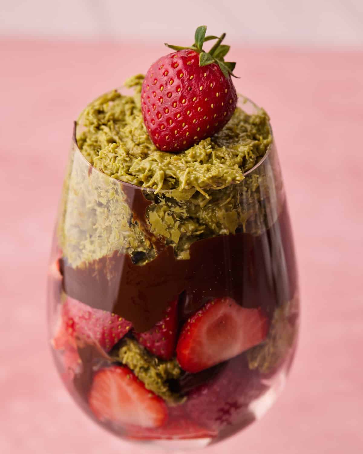 Layers of crunchy pistachio filling, fresh strawberries and melted chocolate in a glass to make Dubai chocolate strawberries.