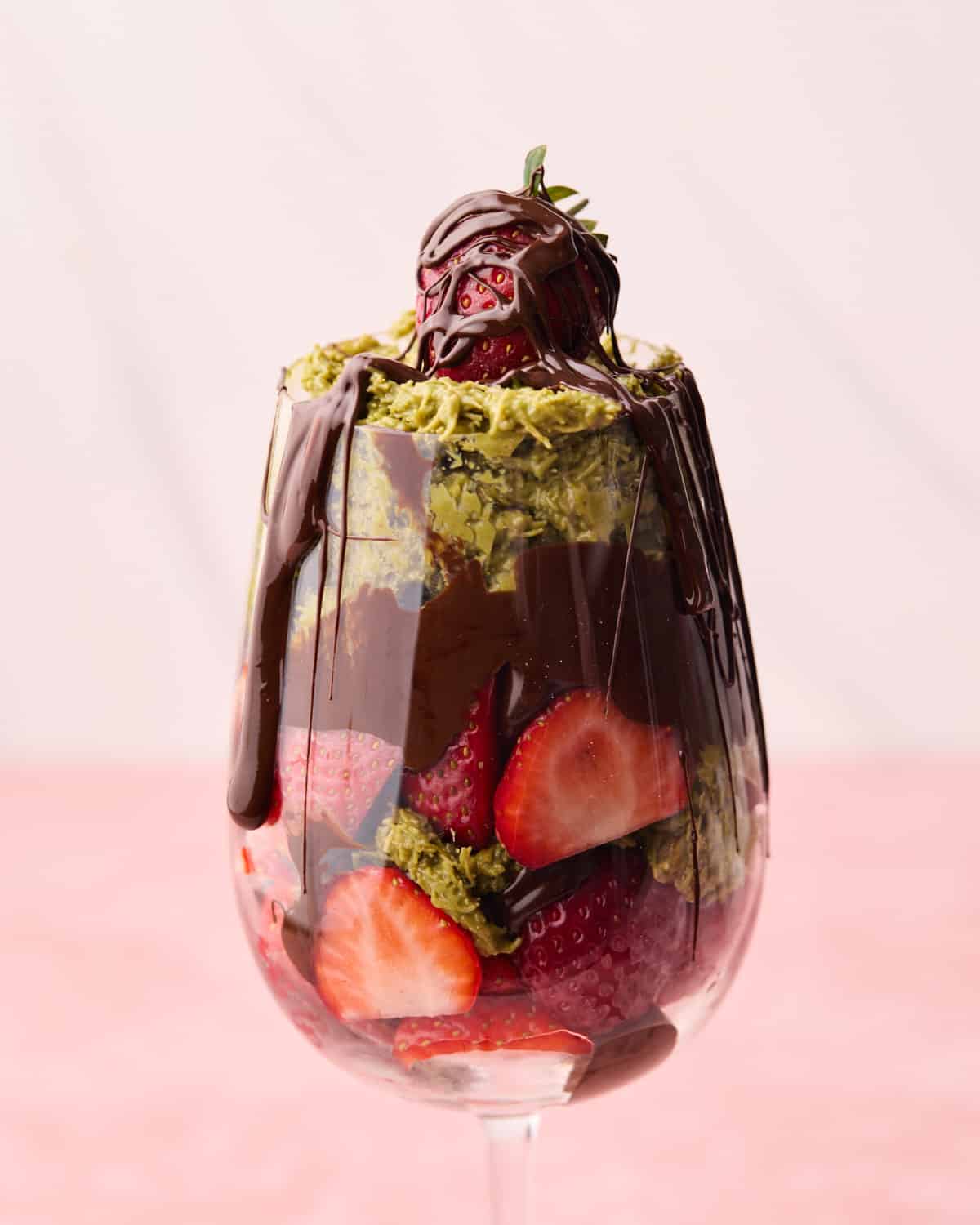 Melted chocolate being drizzled on top of Dubai chocolate strawberries in a glass.