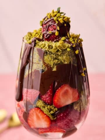 Dubai chocolate strawberries in a glass with melted chocolate dripping down the side.