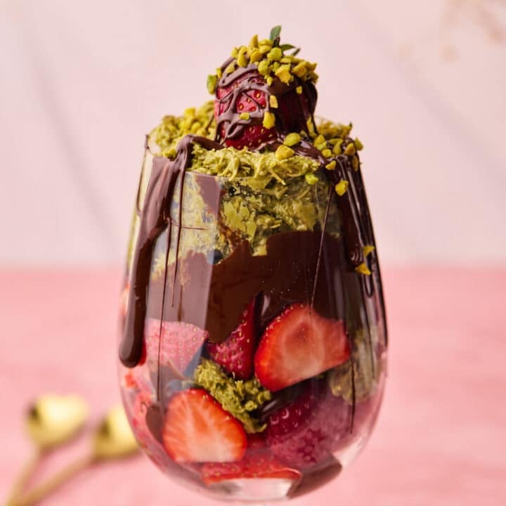 Dubai chocolate strawberries in a glass with melted chocolate dripping down the side.