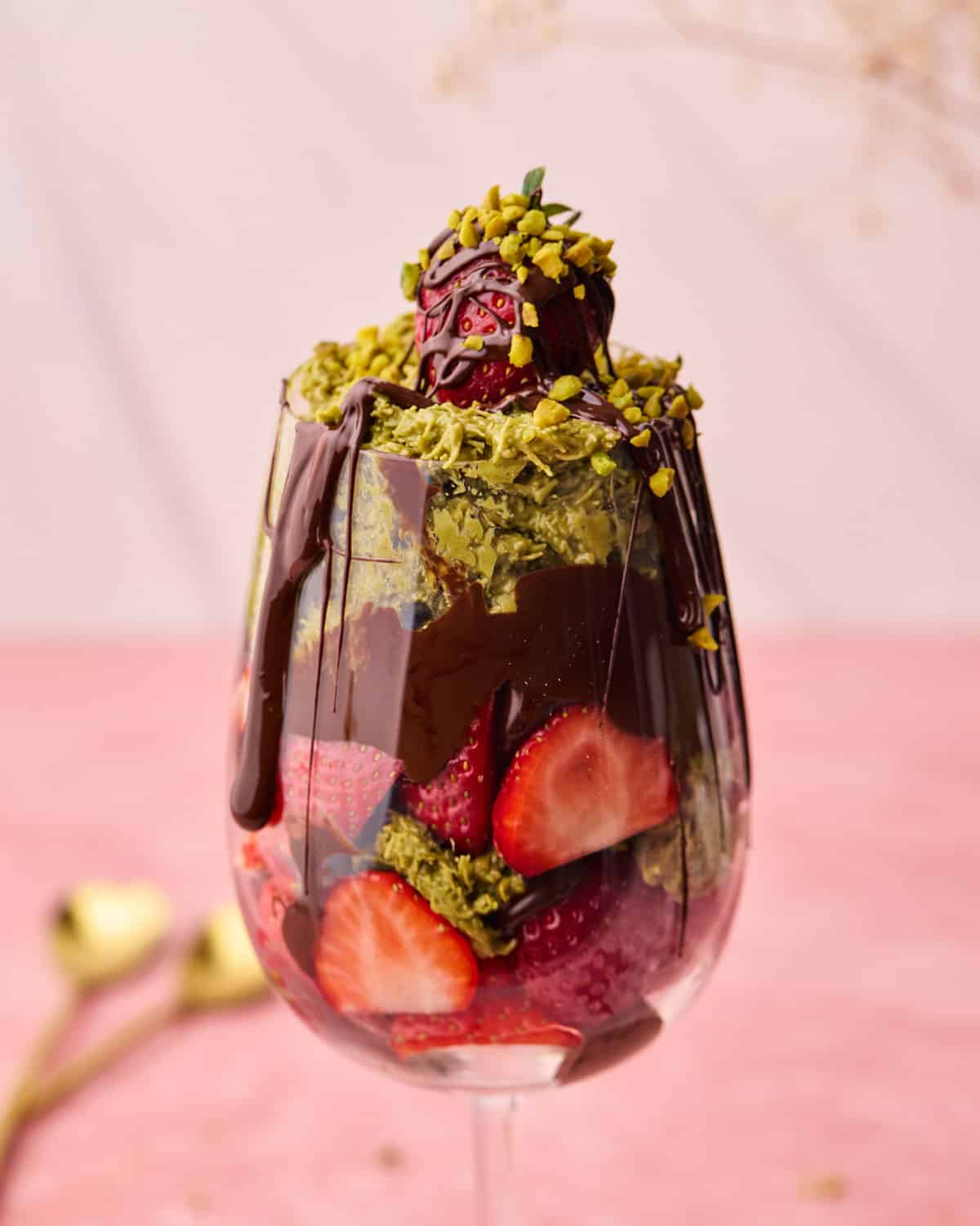 Dubai chocolate strawberries in a glass with melted chocolate dripping down the side.