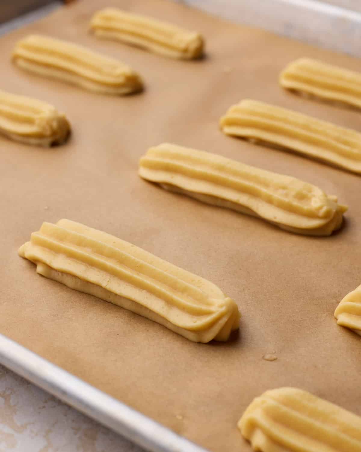 Choux pastry piped onto a baking sheet in long fingers to make eclairs.
