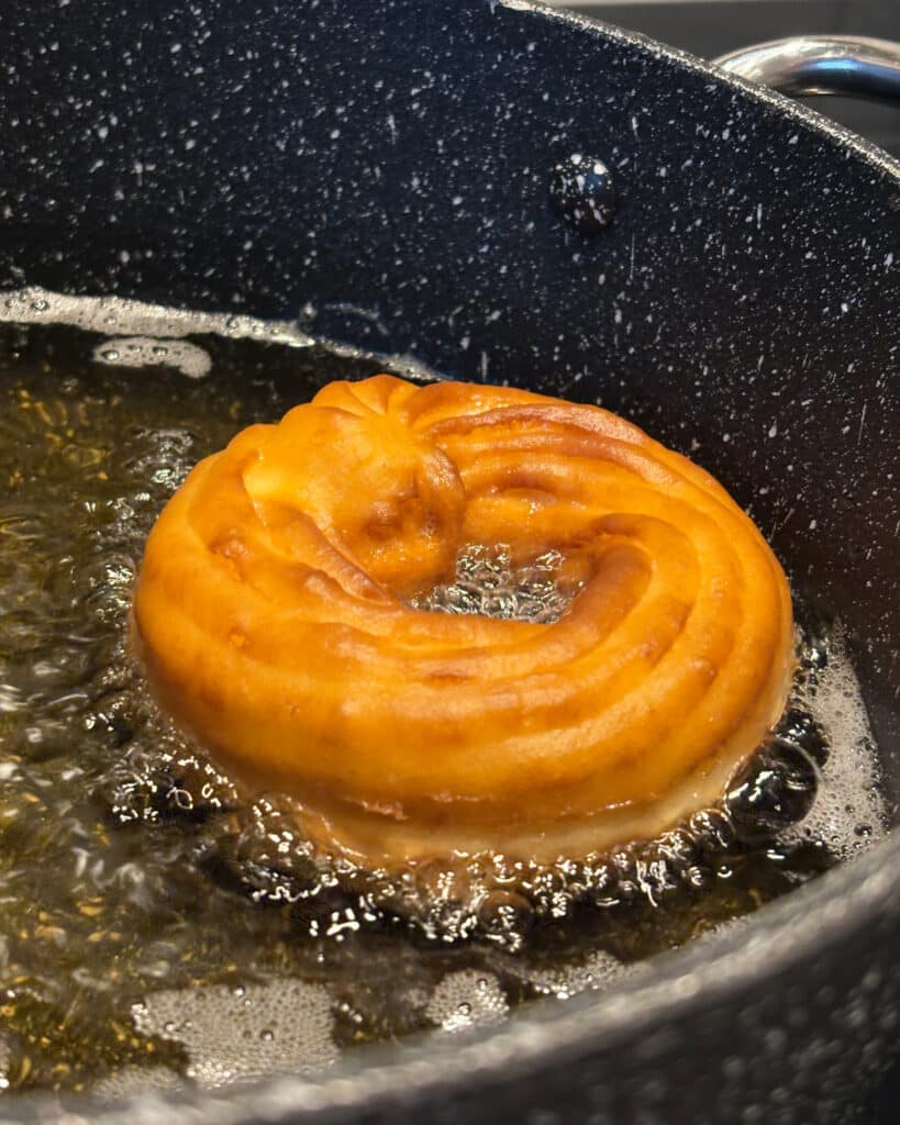 French cruller bubbling away in frying oil.