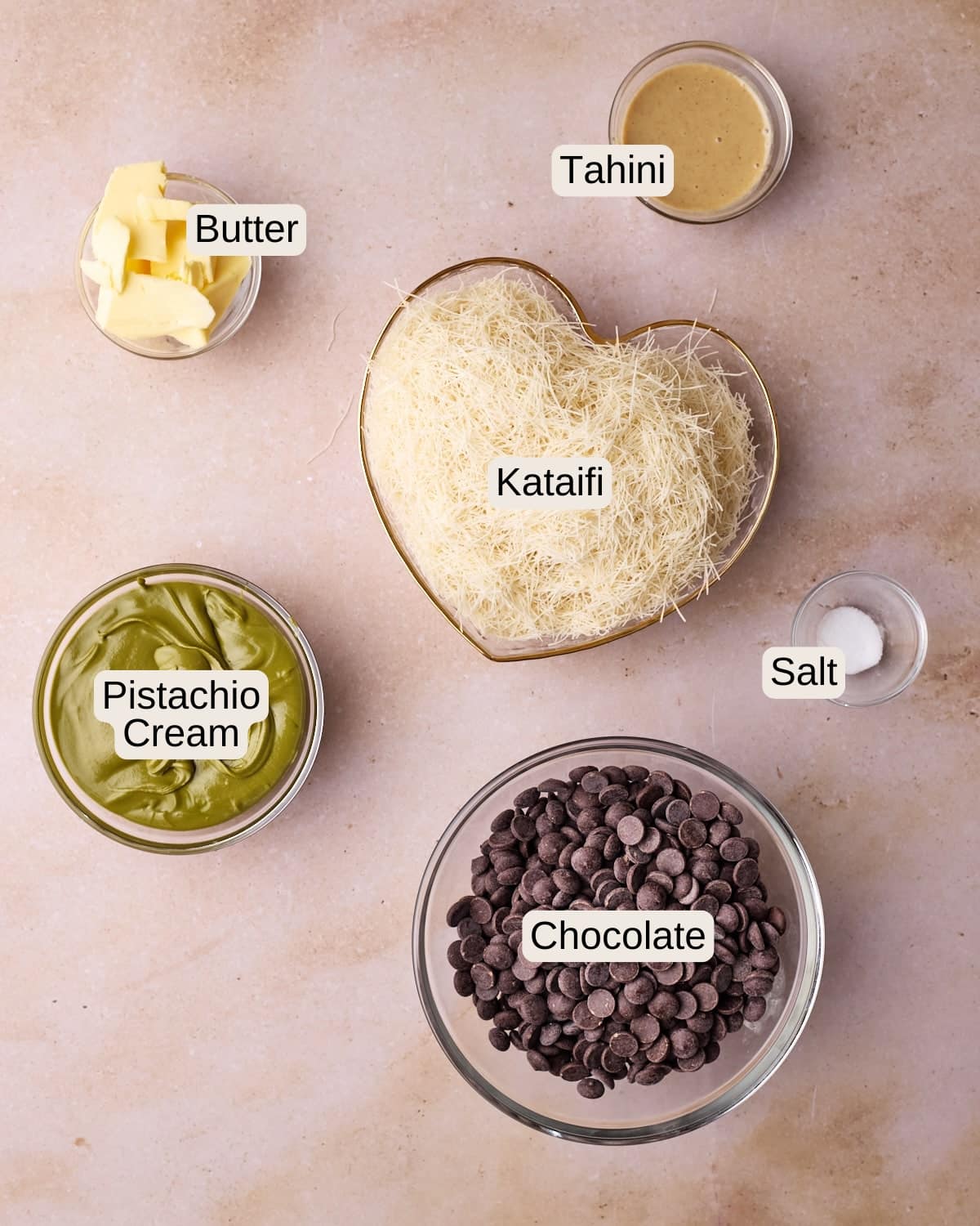 Ingredients for Dubai chocolate strawberries, including butter, tahini, kataifi, pistachio cream, salt, and chocolate.