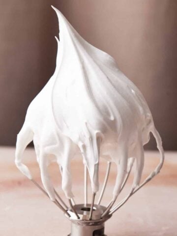 Meringue on a whisk to make marshmallow frosting, one of the many ways to use leftover egg whites.