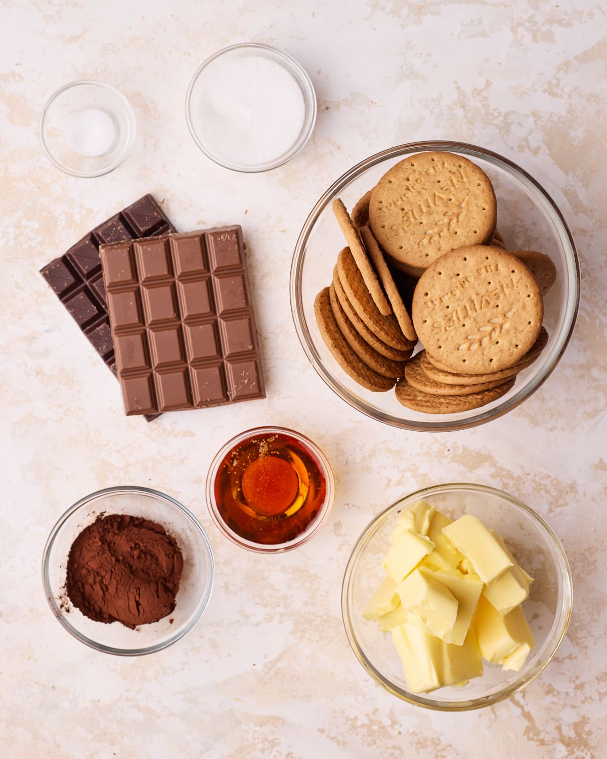 Ingredients to make tiffin - digestive biscuits, chocolate, butter, cocoa powder, golden syrup, sugar, and salt.