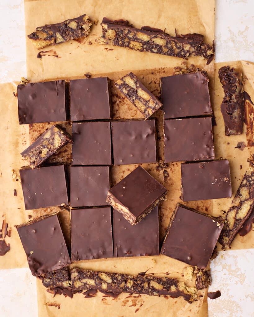 Tiffin being sliced into squares on top of parchment paper.