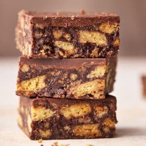 Three squares of Scottish tiffin in a stack, showing the insides with chunks of biscuit in a chocolate filling.