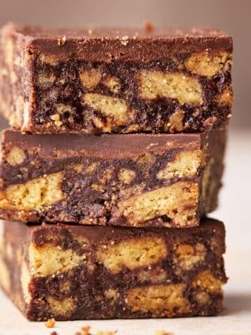 Three squares of Scottish tiffin in a stack, showing the insides with chunks of biscuit in a chocolate filling.