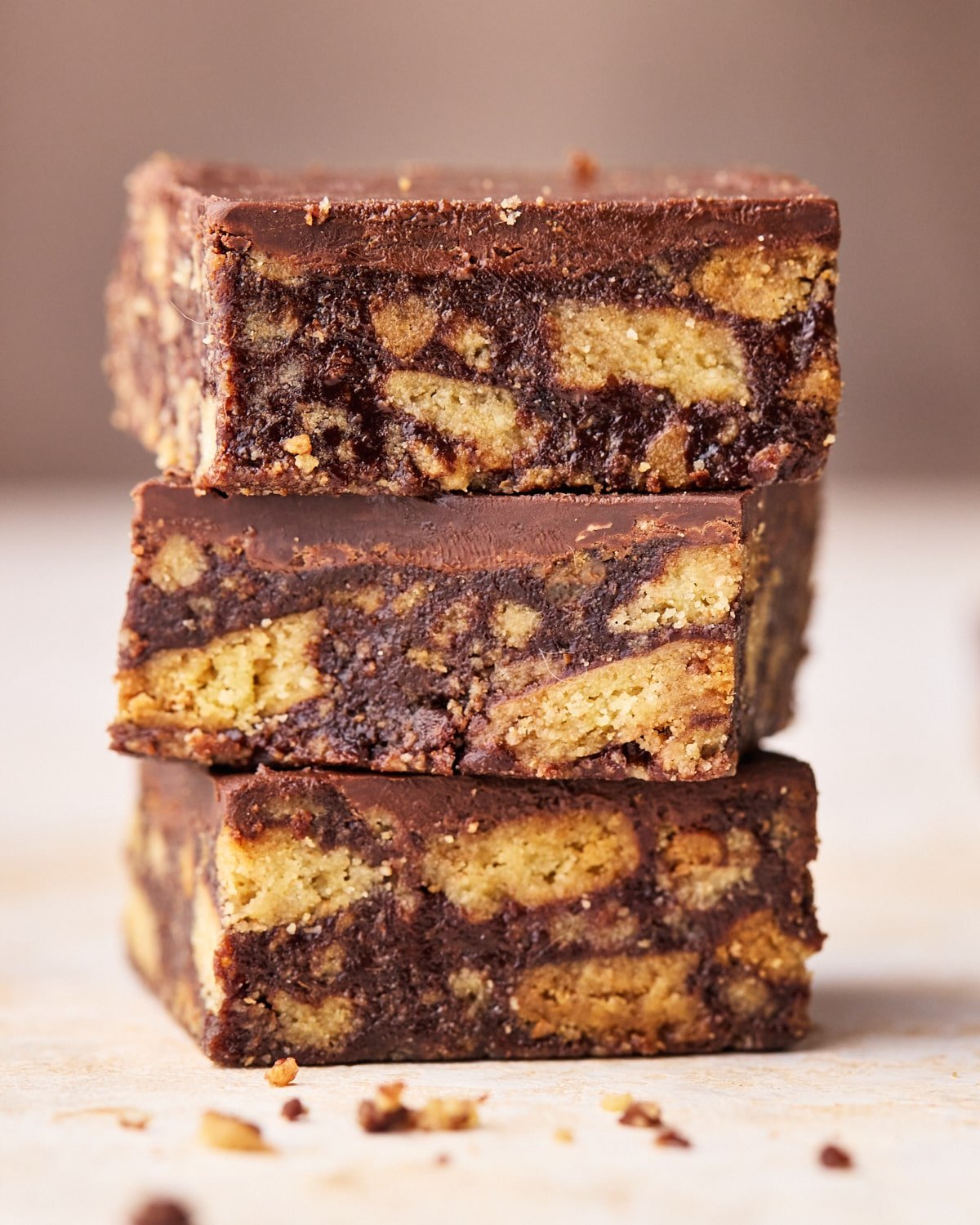 Three squares of Scottish tiffin in a stack, showing the insides with chunks of biscuit in a chocolate filling. 
