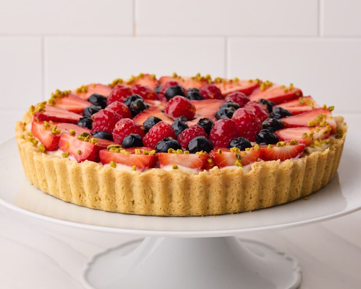 Fresh fruit tart with vanilla pastry cream filling, a shortbread crust, and glazed berries on top.