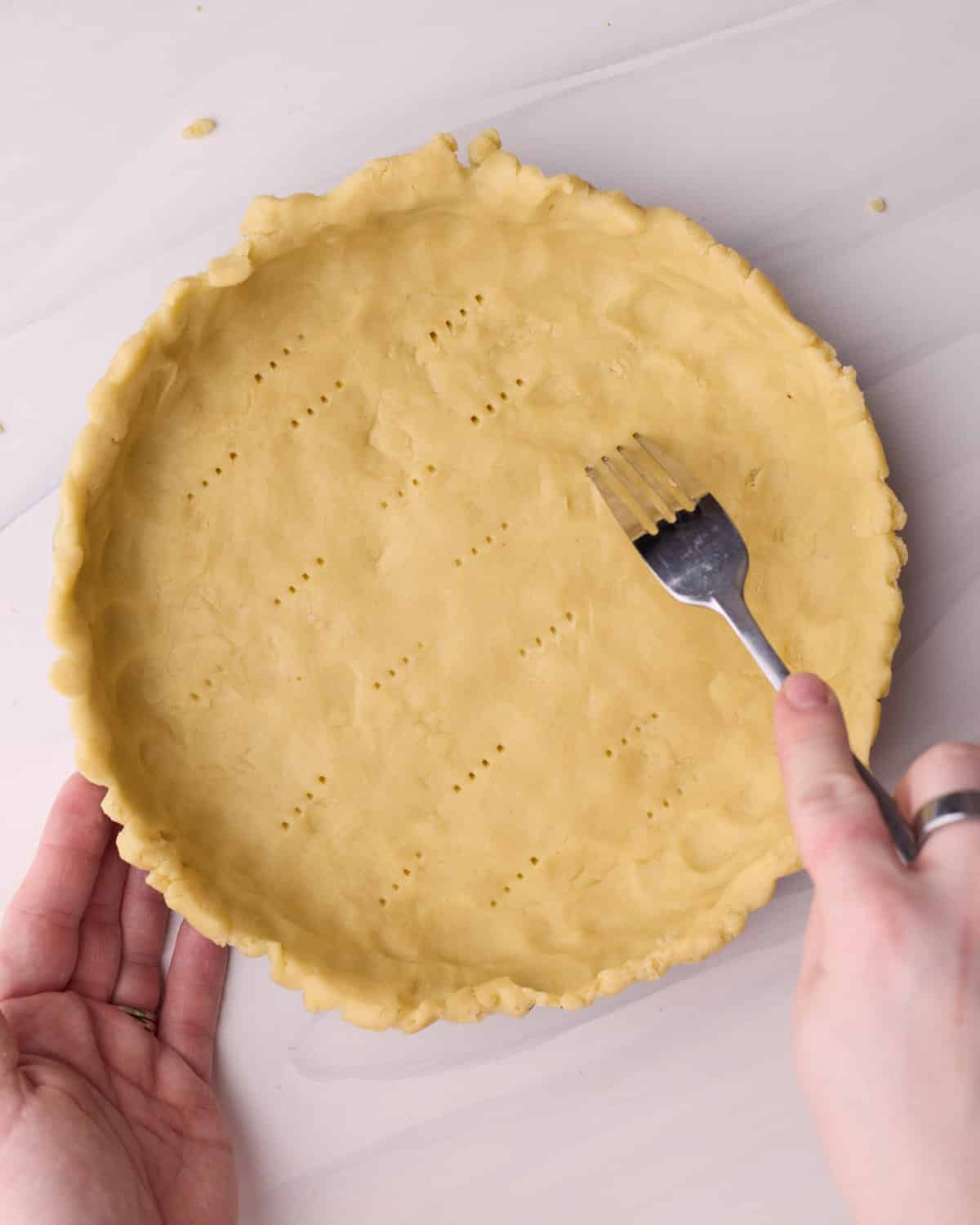 Docking a shortbread crust all over with a fork before baking.