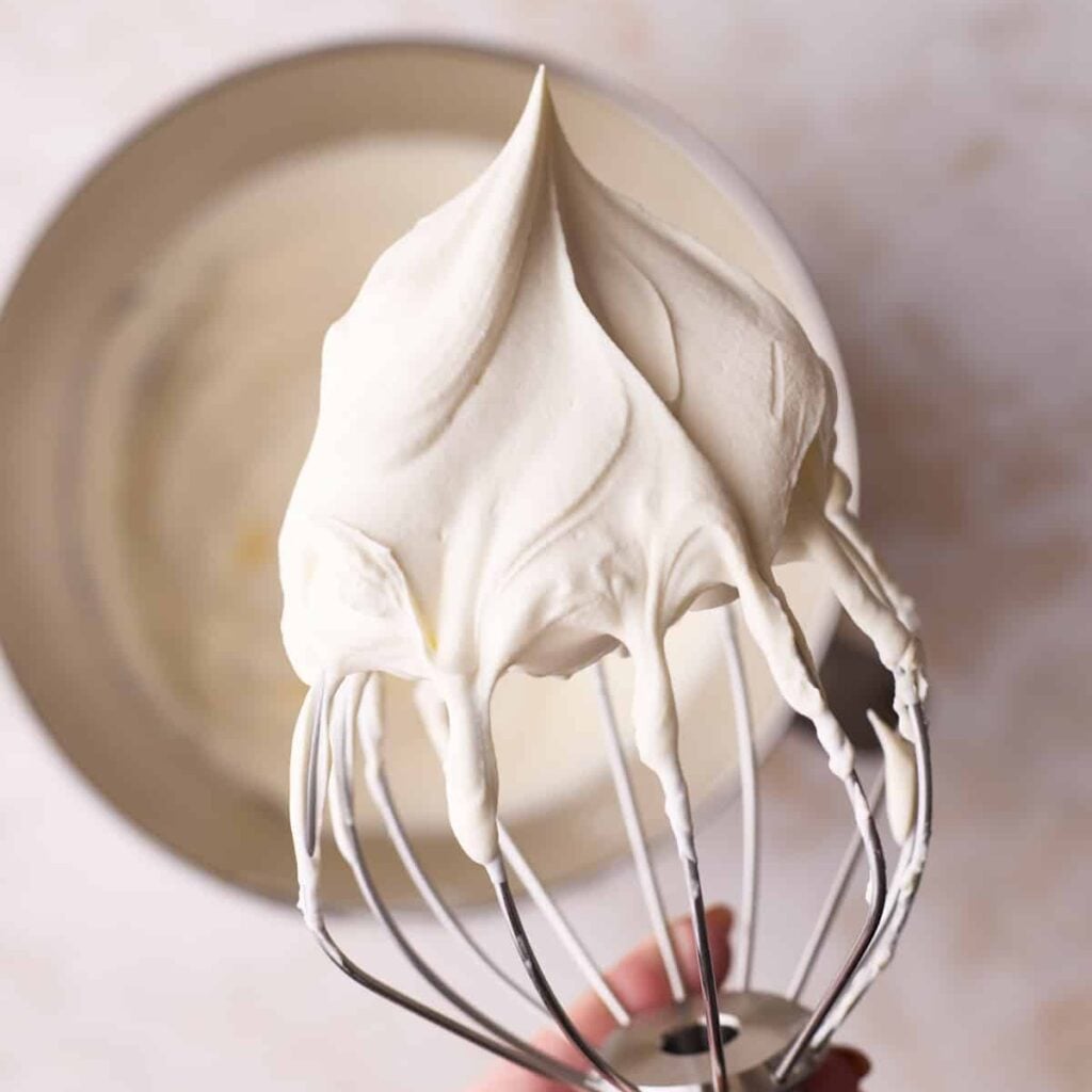 Perfect whipped cream on a whisk with stiff peaks.