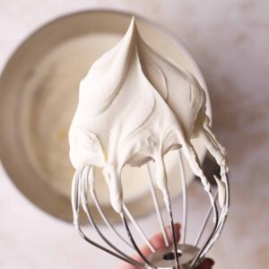 Perfect whipped cream on a whisk with stiff peaks.