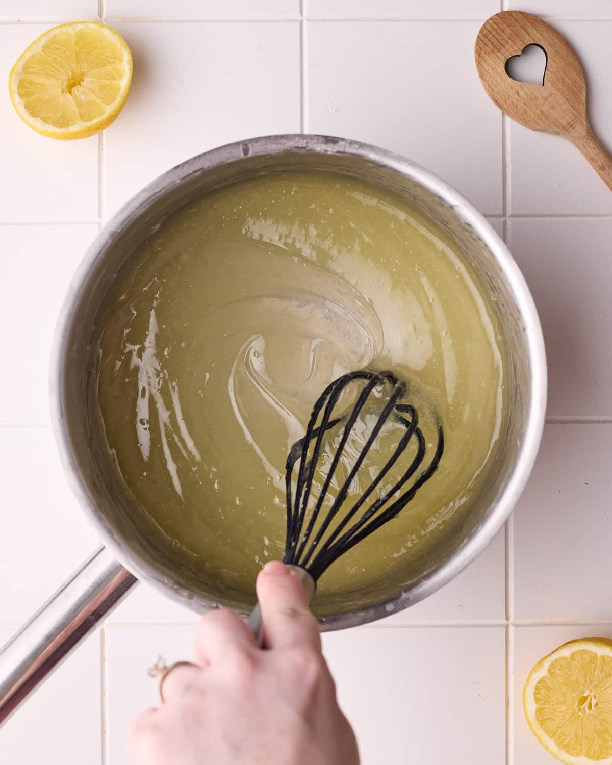 Lemon meringue pie filling being whisked in a saucepan until thickened and clear.
