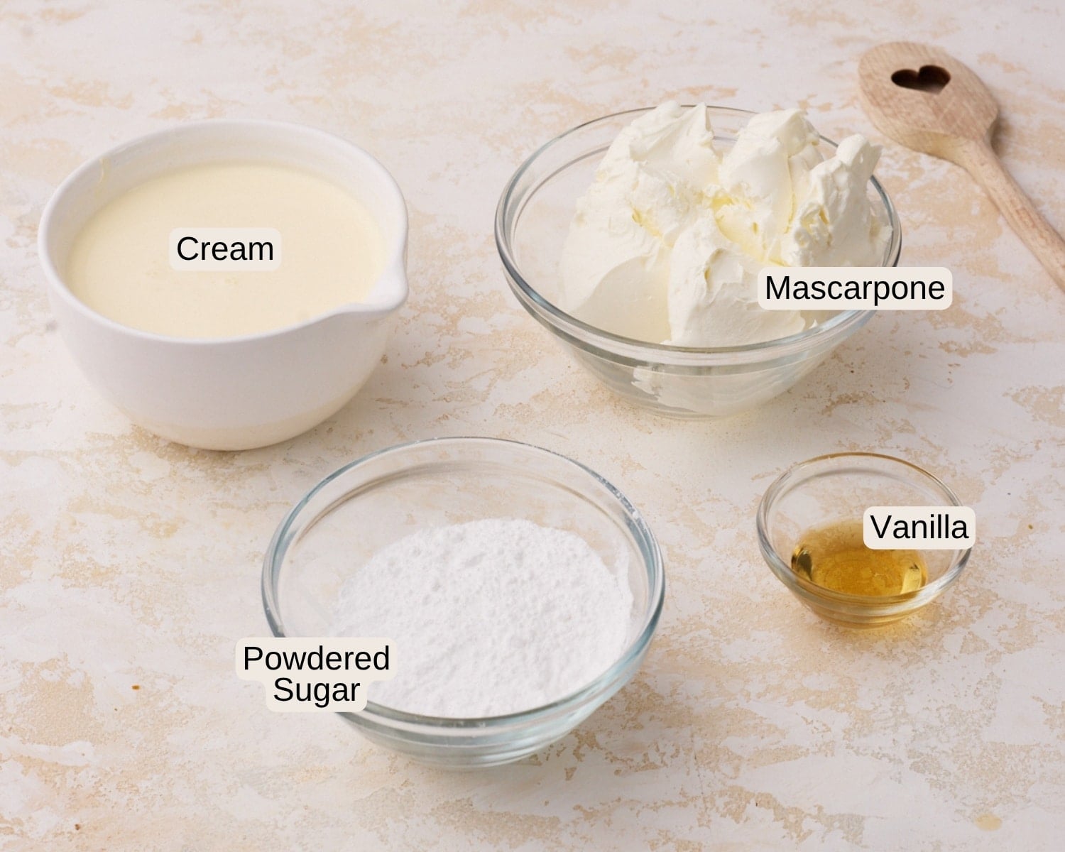 ingredients to make mascarpone cream without eggs, including mascarpone cheese, heavy cream, powdered sugar and vanilla.