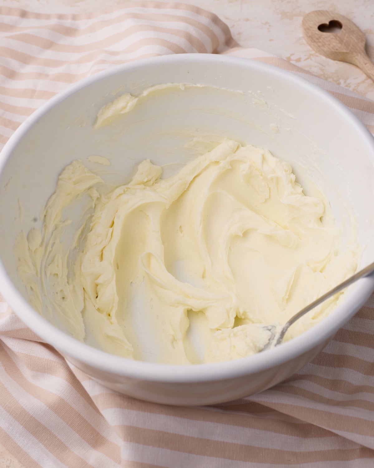 Mixing mascarpone cheese and powdered sugar in a bowl to make mascarpone cream.