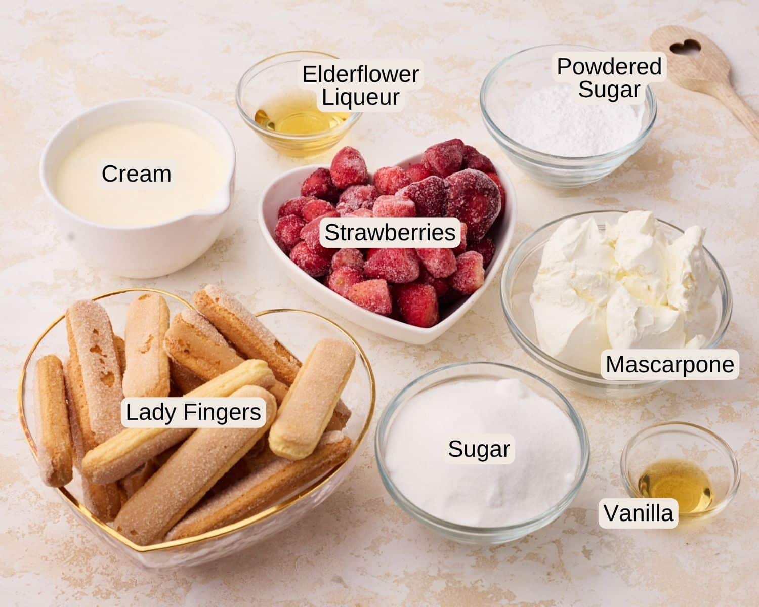 Ingredients to make strawberry tiramisu including ladyfingers, strawberries, sugar, mascarpone cheese, heavy cream, powdered sugar, vanilla and elderflower liqueur.