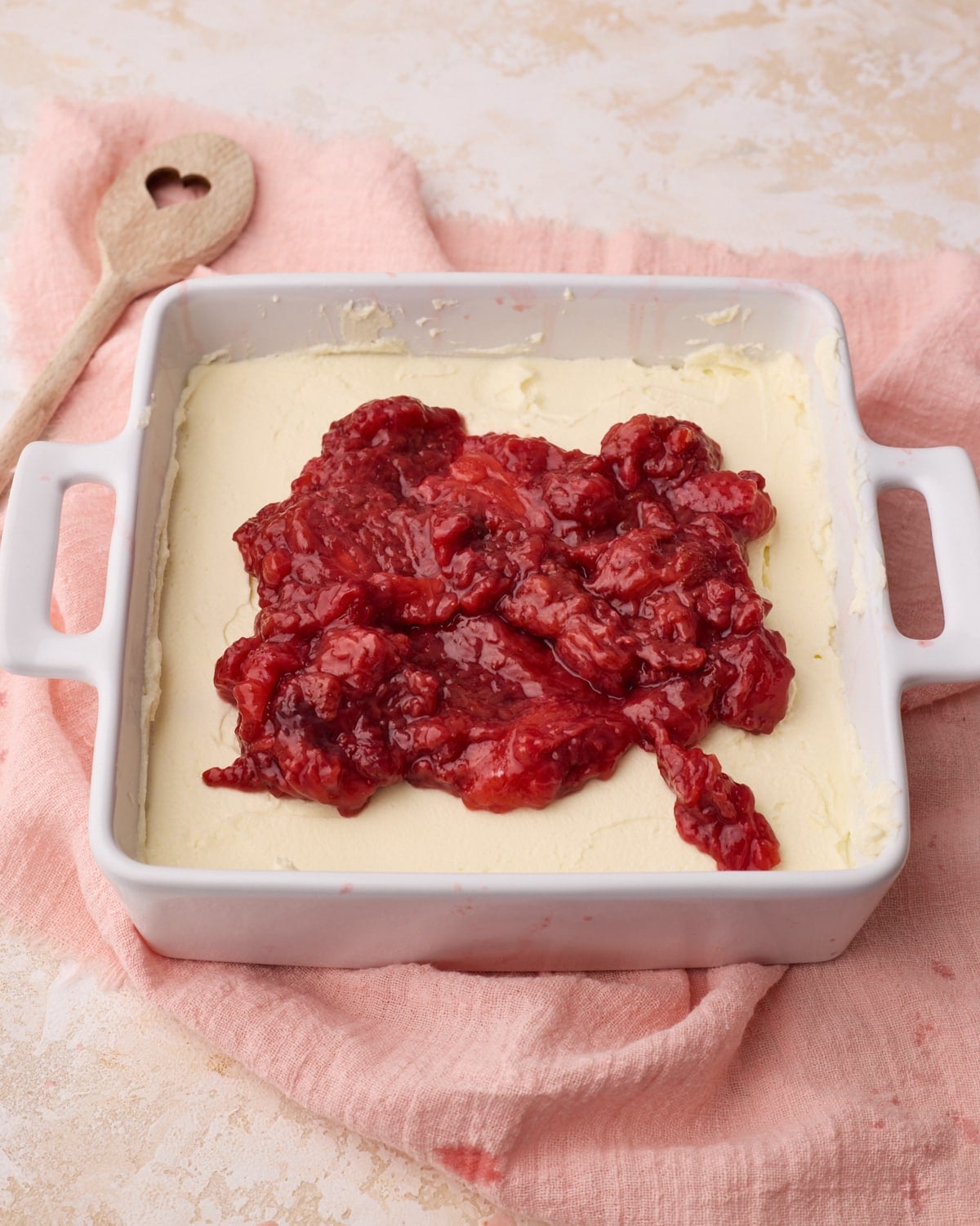 Strawberry filling being added on top of mascarpone cream to make strawberry tiramisu.