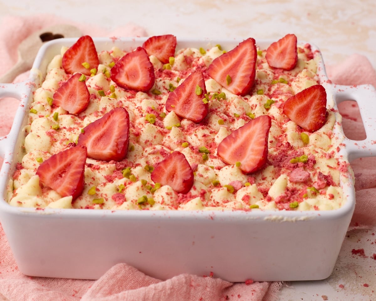 Strawberry tiramisu topped with piped mascarpone cream, fresh strawberries and chopped pistachios.