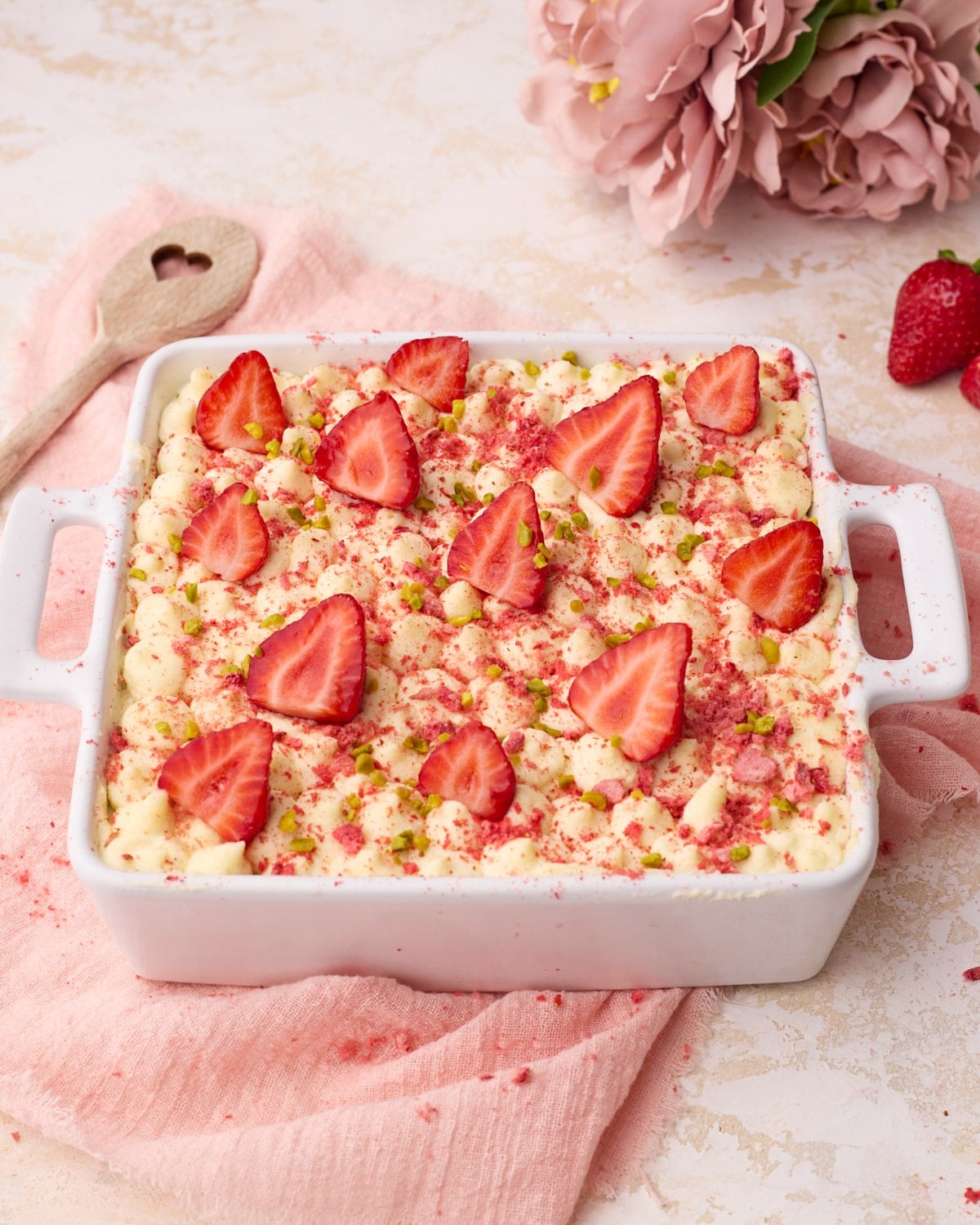 Strawberry tiramisu decorated with fresh strawberry slices, crushed freeze dried strawberries, and some chopped pistachios.