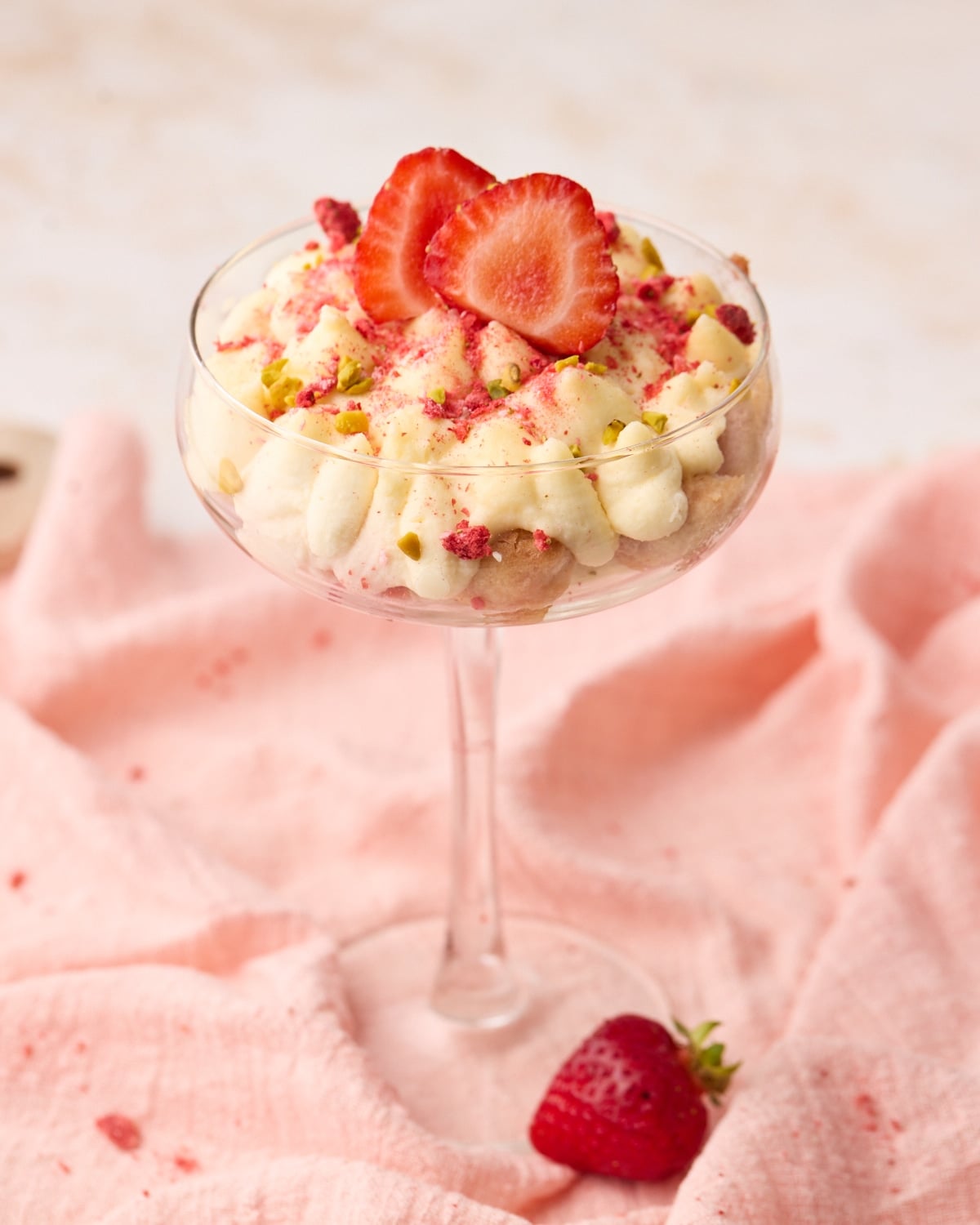 Strawberry tiramisu served as an individual portion in a coupe glass with ladyfingers, mascarpone cream, and fresh strawberries.