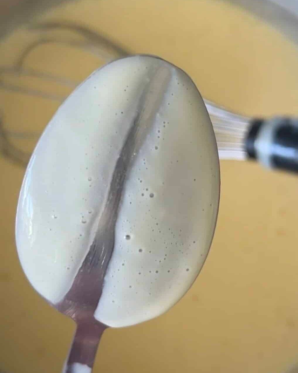 Showing the nappe phase of creme anglaise by coating the back of a spoon and drawing a line in it.